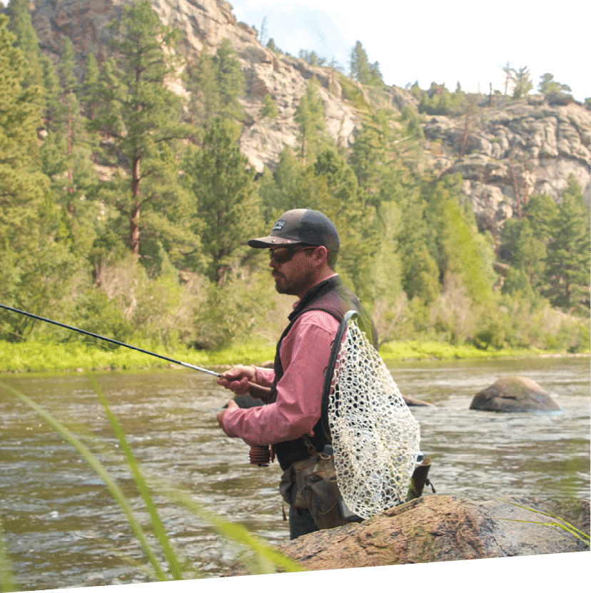 A man is standing on a rock near a river, holding a fishing rod. AI generated content